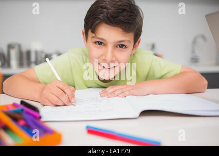 Smiling boy doing homework in kitchen Stock Photo