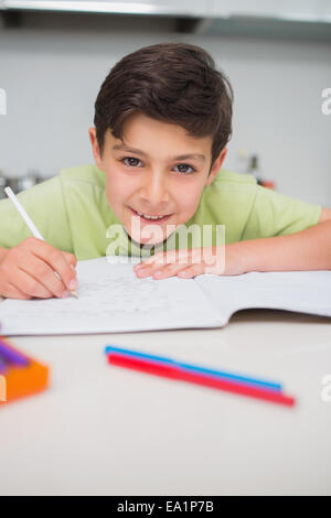 Smiling boy doing homework in kitchen Stock Photo