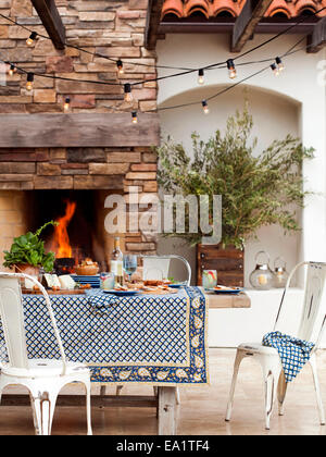 Outdoor dining scene with set table and fire Stock Photo