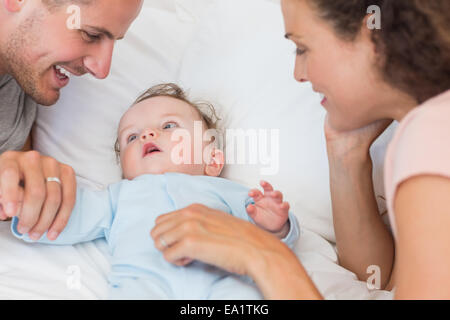 Parents looking at baby boy in bed Stock Photo