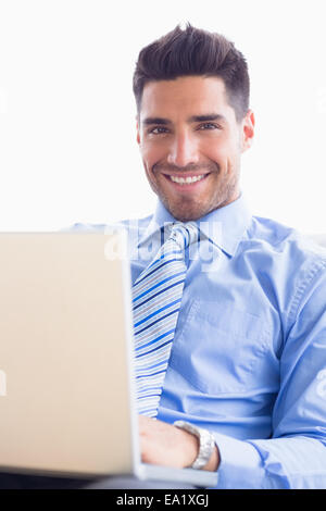 Happy businessman on couch using his laptop Stock Photo