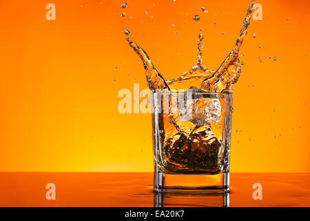 Whiskey Splash Out Of Glass On Yellow Background Stock Photo Alamy