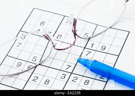 Suduko numbers puzzle spectacles and pen close-up to illustrate a mental health healthy mind concept. Stock Photo