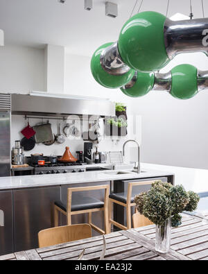 Modern kitchen with marble work top and bar stools. The green lamp designed by Andy Martin Stock Photo