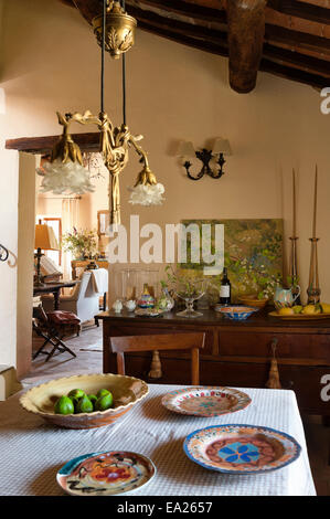 Brightly coloured plates on table in dining room with sideboard and artwork Stock Photo