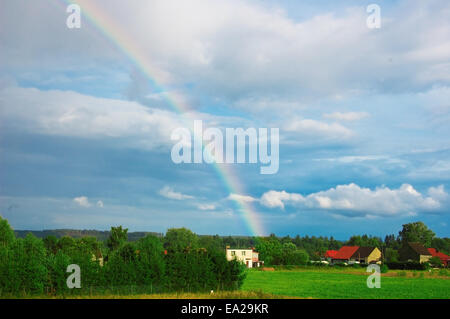 Rainbow over the small village. Stock Photo