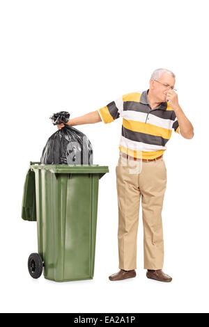 Full length portrait of a senior throwing away a stinky bag of trash isolated on white background Stock Photo