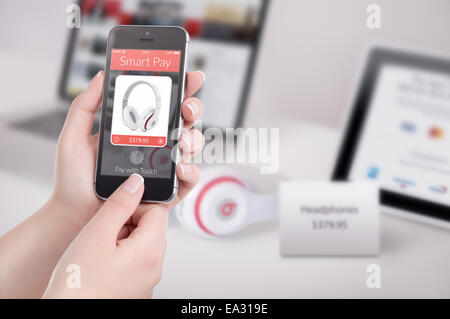 Woman is buying headphones by black mobile smart phone with nfc smart pay application on the screen. Purchase of headphones by f Stock Photo