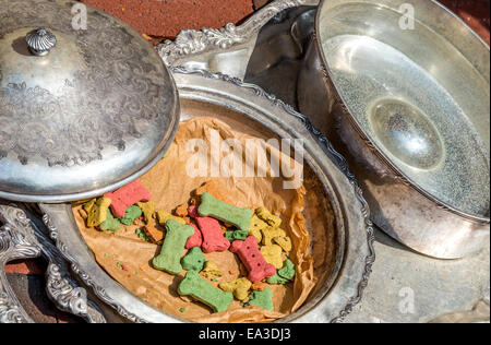 Dog biscuits and water in silver dinnerware. Stock Photo