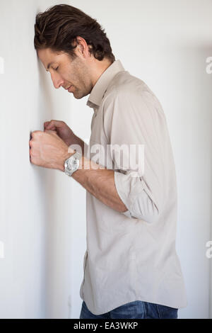 Casual worried businessman leaning on wall Stock Photo