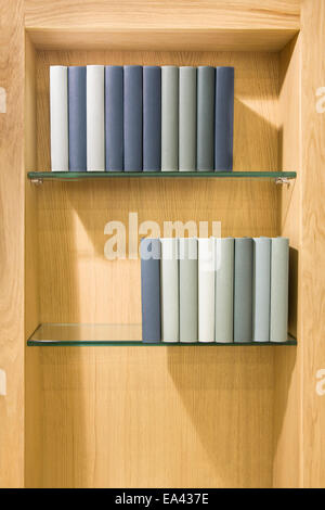 Various books on the glass shelf in a wooden cabinet Stock Photo