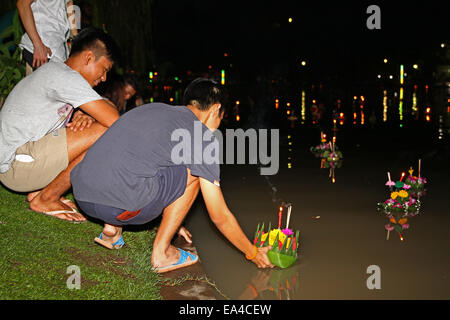 Chatuchak Park's lake, Bangkok, Thailand. 6th November 2014. A young man places his krathong (small vessel) in the water during Loi Krathong, an annual Thai festival during which people give thanks to the goddess of water (Phra Mae Khongkha) and seek forgiveness for past misdeeds. Credit:  Maria J Atkins/Alamy Live News Stock Photo