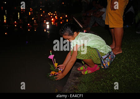 Chatuchak Park's lake, Bangkok, Thailand. 6th November 2014. A little girl places her krathong (small vessel) in the water during Loi Krathong, an annual festival during which people give thanks to the goddess of water (Phra Mae Khongkha) and seek forgiveness for past misdeeds. Credit:  Maria J Atkins/Alamy Live News Stock Photo