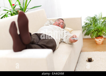 Senior man relaxing on sofa and looking to television Stock Photo