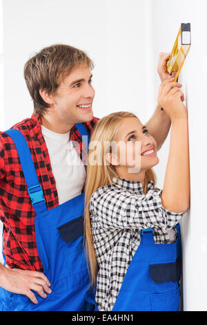 Repairman helping woman to use builder level Stock Photo