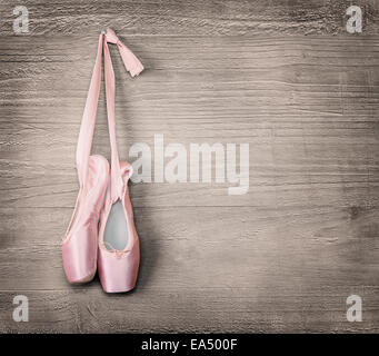 New pink ballet shoes hanging on wooden background.Vintage style. Stock Photo