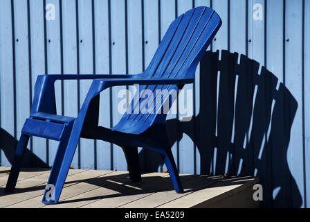 A blue deckchair against a blue wall Stock Photo