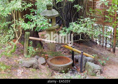 Tsukubai Water Fountain with Stone Basin and Bamboo Spigot and Stone Lantern at Portland Japanese Garden Stock Photo