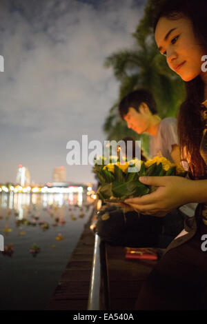 Benjakiti Park, Bangkok, Thailand, 6th November 2014. A young Thai woman prepares to float her krathong (decorated basket) on the lake of Benjakiti Park to celebrate the annual Loi Krathong festival. Loi Krathong is an annual festival celebrated in Thailand to give thanks to the Goddess of Water, Phra Mae Khongkha. Credit:  Alison Teale/Alamy Live News Stock Photo