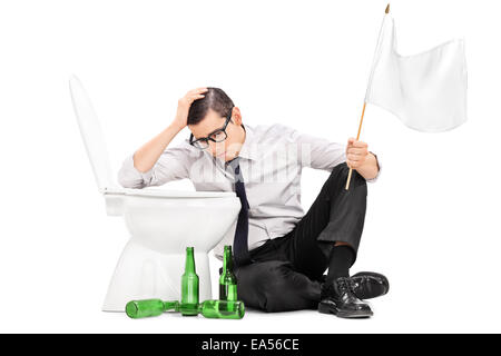Drunk man sitting by a toilet and holding white flag isolated on white background
