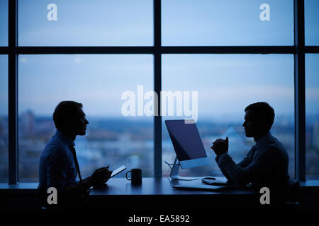 Outlines of two businessmen working late in office Stock Photo