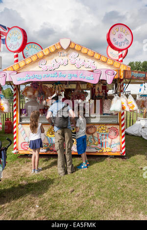 Man buying sweets for children from a stall selling sugary snacks at an English summer fair. Stock Photo