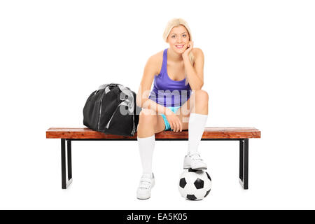 Female soccer player sitting on a bench isolated on white background Stock Photo