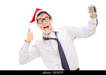 Guy covered in lipstick kisses giving a thumb up and taking a selfie isolated on white background Stock Photo