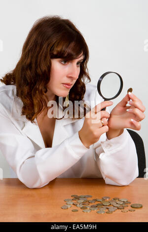 hand hold magnifying glass and coins Stock Photo