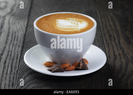 cup of freshly made cappuccino with latte art, on oak table Stock Photo