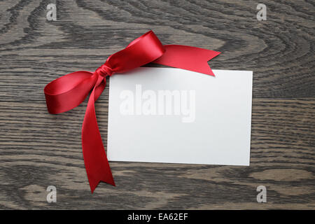 red bow with paper card, on old wooden table Stock Photo