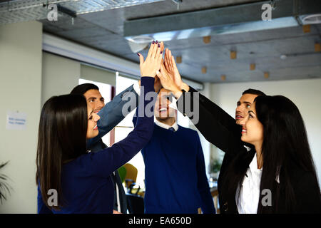 Happy business team is holding hands together. Raising one hand up Stock Photo