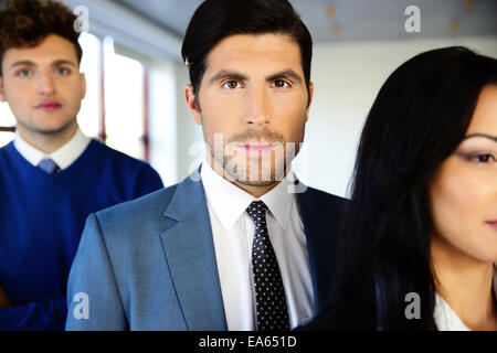 Group of a young serious businesspeople standing in office Stock Photo