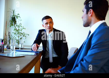 Two businessmen discussing tasks sitting at office table Stock Photo