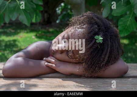 Young girl napping with her head resting on table Stock Photo