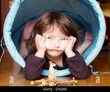 Portrait of girl lying in a plastic play tunnel Stock Photo