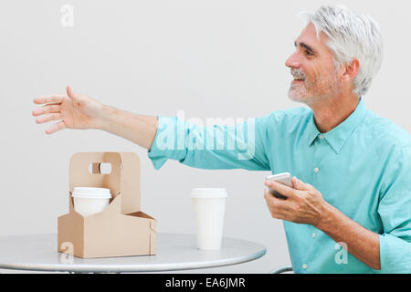 Businessman at outdoor cafe greeting someone Stock Photo