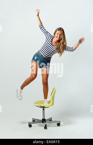 girl standing on a chair balancing Stock Photo