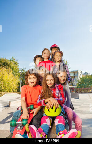 Happy friends sitting with skateboards and helmets Stock Photo