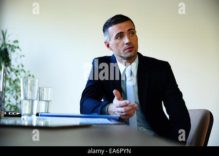 Businessman sitting at the table and explaining something Stock Photo
