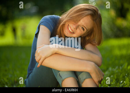 beautiful red-haired girl sitting on grass Stock Photo
