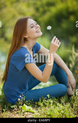 Girl With Daisies Sits On The Grass And Sniff It Stock Photo - Alamy