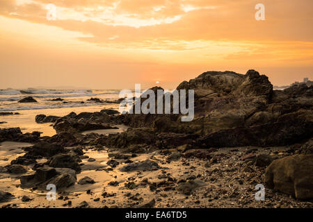 sunset at the rocky beach in cloudy day Stock Photo