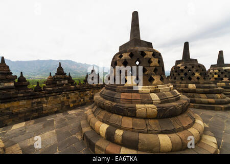 Latticed stone stupas containing Buddha statues on the upper terrace, Borobudur Temple Compounds, Central Java, Indonesia Stock Photo