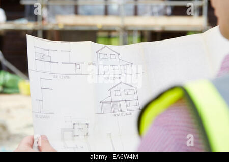 Architect On Building Site Looking At Plans For House Stock Photo