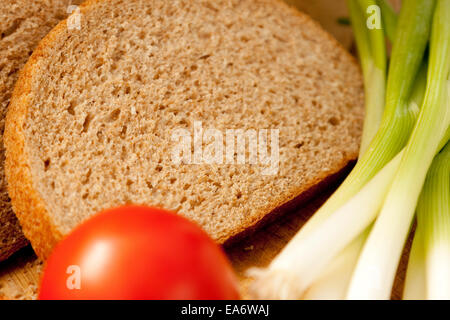 wholemeal (wholewheat) bloomer bread slices presented with spring onions and a tomato Stock Photo