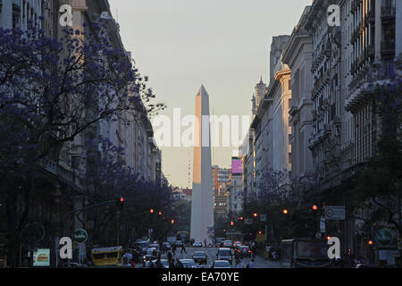 The Buenos Aires Obelisk at dusk in springtime, with Jacaranda trees in bloom on 'Diagonal Norte'. Argentina. Stock Photo
