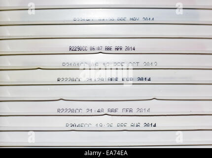 The side of old ice cream tub lids stacked on top of each other, some showing expiry and use by dates. Stock Photo