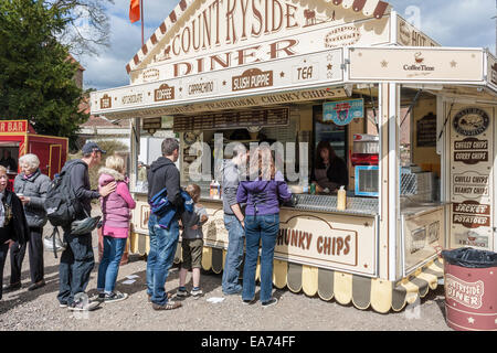 Take away stall at a summer fair selling chips and drinks to queueing customers. Stock Photo