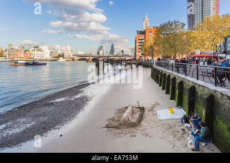 Sand sofa sculpture on the Embankment of the River Thames, London near Oxo Tower, with Blackfriars Bridge and iconic buildings Stock Photo